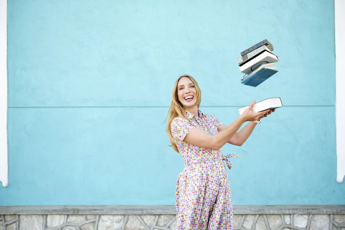 Jana Marie Backhaus-Tors wirft Bücher in die Luft vor einer hellblauen Wand